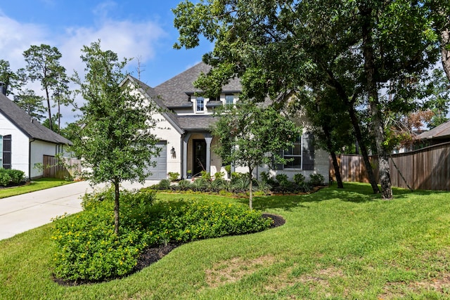 view of front of house with driveway, a front lawn, an attached garage, and fence