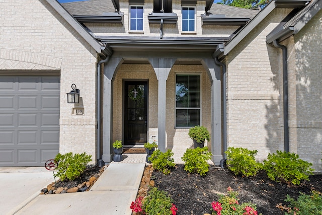 entrance to property with an attached garage, roof with shingles, and brick siding