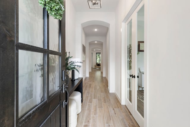 interior space with baseboards, arched walkways, and wood finish floors