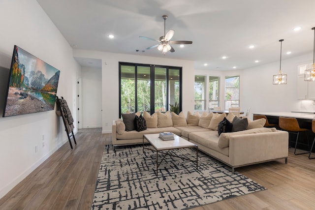 living room featuring visible vents, baseboards, wood finished floors, and recessed lighting