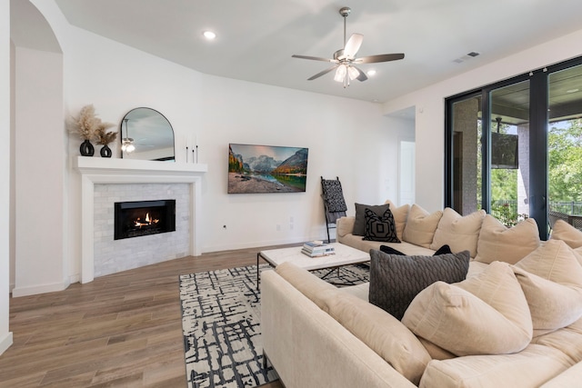 living area featuring baseboards, visible vents, a ceiling fan, wood finished floors, and a fireplace