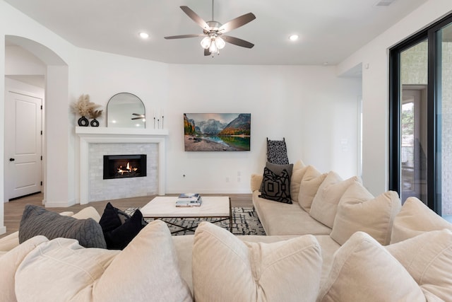 living area featuring baseboards, a lit fireplace, wood finished floors, and recessed lighting