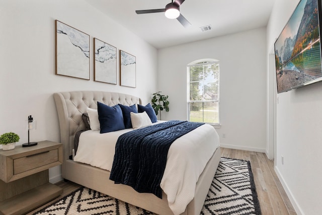 bedroom featuring light wood-type flooring, baseboards, visible vents, and a ceiling fan