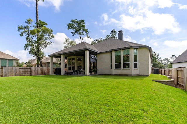 back of property with a patio, a lawn, a chimney, and a fenced backyard