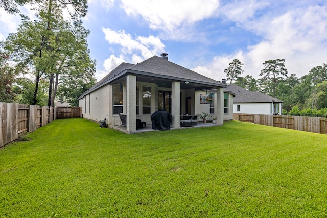 rear view of house featuring a fenced backyard, a shingled roof, a lawn, and a patio