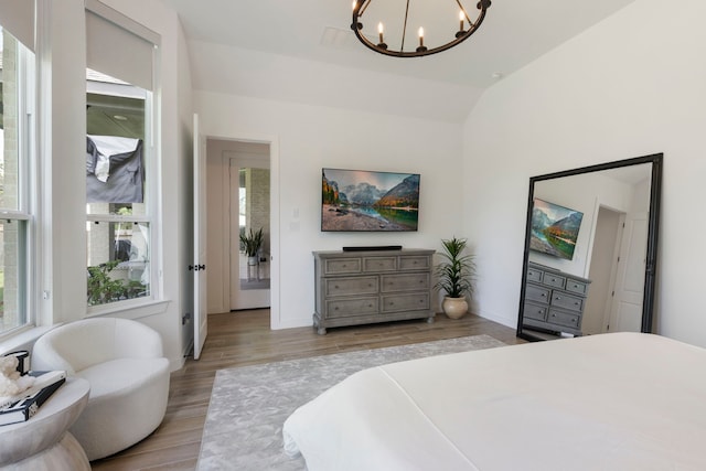 bedroom featuring lofted ceiling, baseboards, a chandelier, and wood finished floors