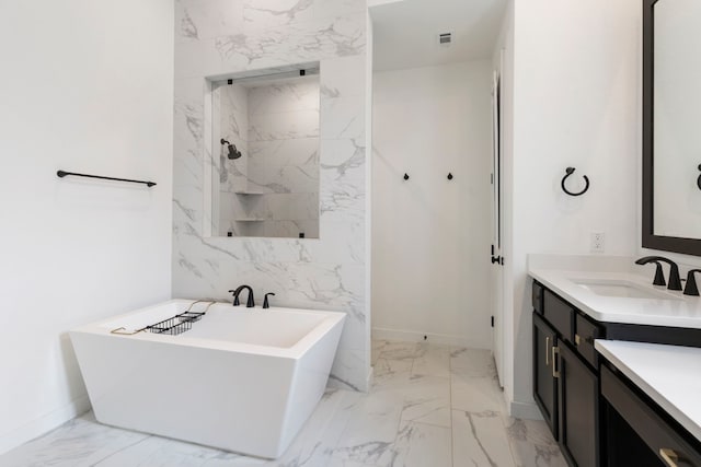 bathroom featuring marble finish floor, visible vents, vanity, a freestanding tub, and baseboards