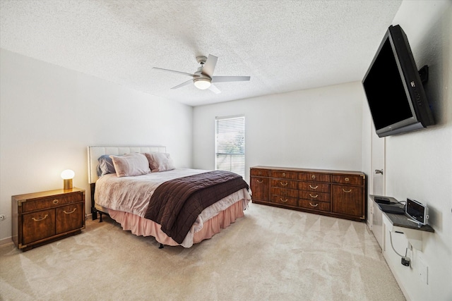 bedroom featuring light colored carpet, ceiling fan, and a textured ceiling