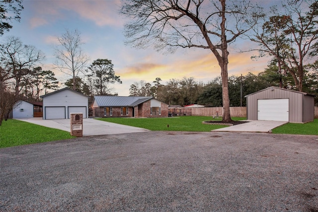 view of front facade with an outbuilding, a yard, a detached garage, and fence