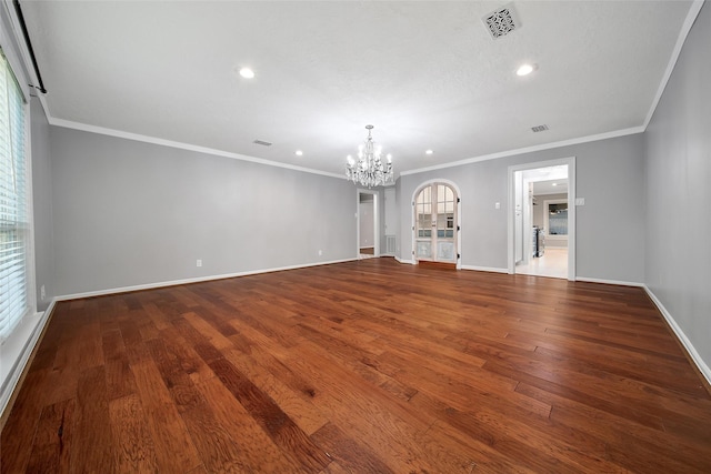 spare room featuring a chandelier, visible vents, baseboards, and wood finished floors