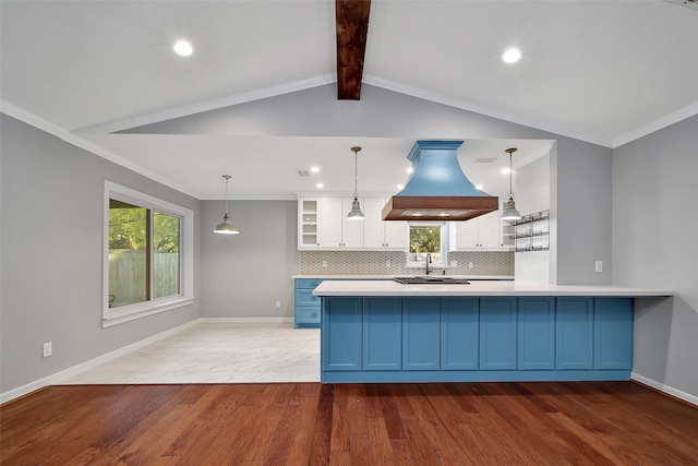 kitchen with island exhaust hood, baseboards, white cabinets, and decorative backsplash