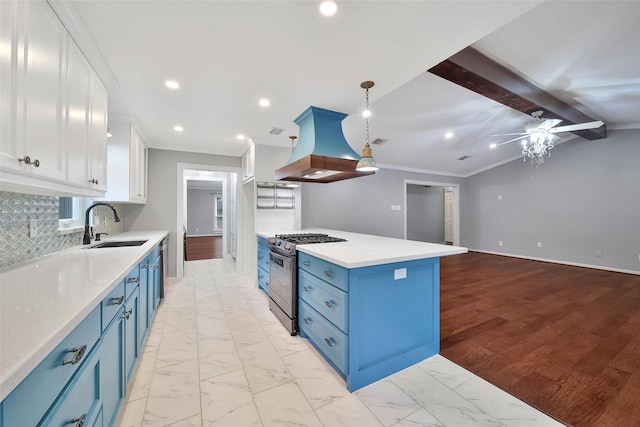 kitchen with marble finish floor, island exhaust hood, blue cabinetry, a sink, and stainless steel gas range oven