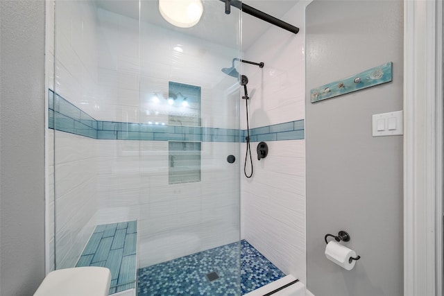 bathroom with a tile shower and toilet