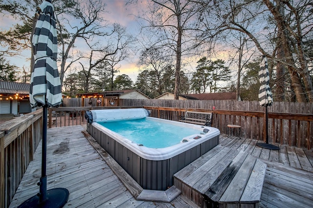 deck at dusk with hot tub deck surround and a fenced backyard