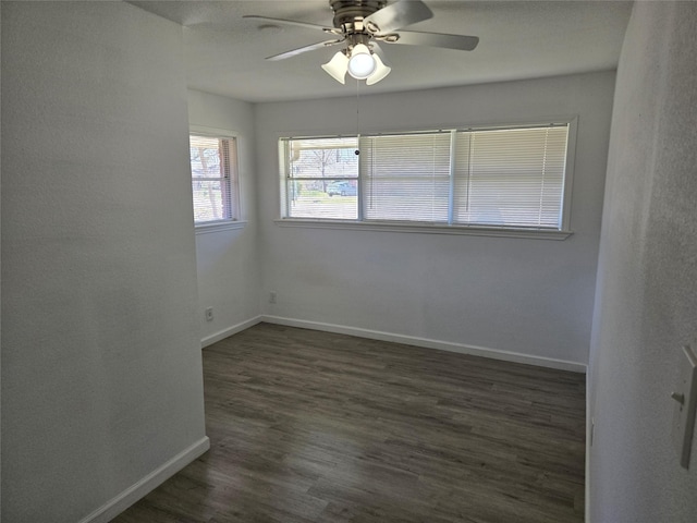 spare room with dark wood-style flooring, a ceiling fan, and baseboards