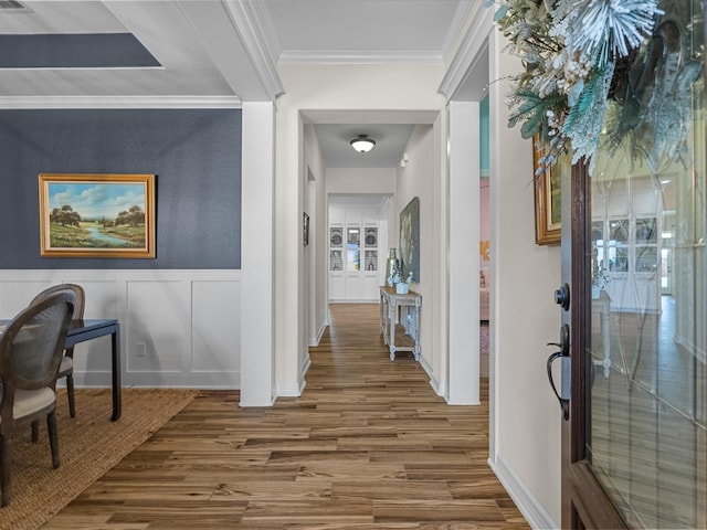 entrance foyer featuring ornamental molding, wainscoting, wood finished floors, and a decorative wall