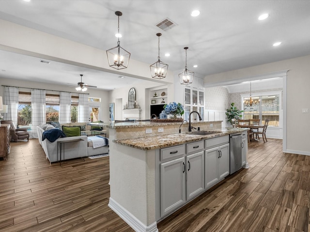 kitchen with dark wood finished floors, open floor plan, a sink, and stainless steel dishwasher