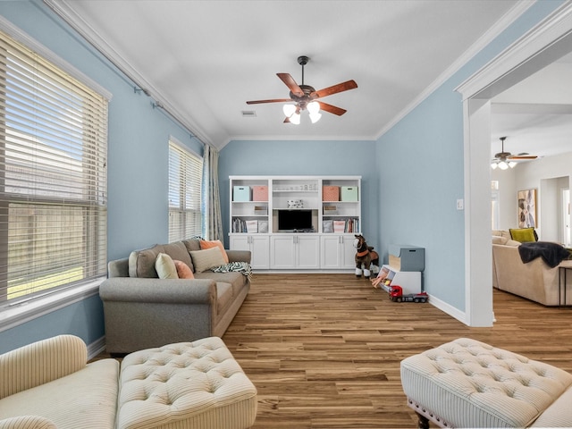 living room with visible vents, ornamental molding, a ceiling fan, wood finished floors, and baseboards