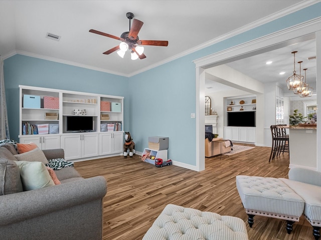 living area with a fireplace, wood finished floors, visible vents, and crown molding