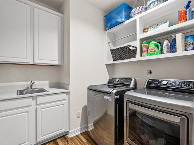 laundry room with wood finished floors, a sink, baseboards, cabinet space, and washer and clothes dryer