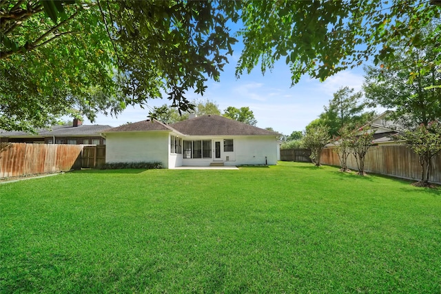 rear view of property featuring a lawn and a fenced backyard