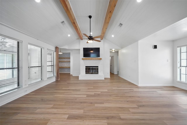 unfurnished living room featuring lofted ceiling with beams, a brick fireplace, light wood-style flooring, and visible vents