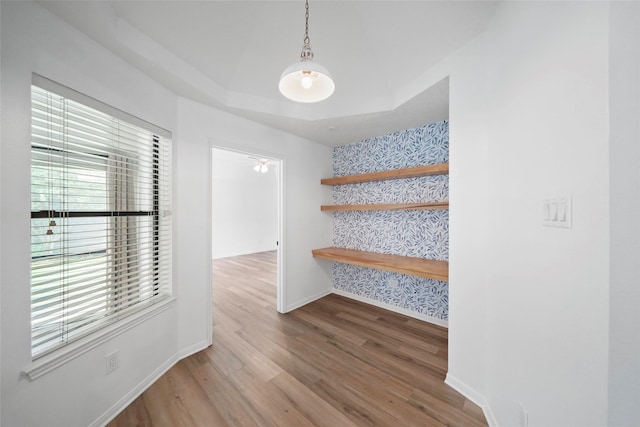 interior space with a tray ceiling, stairway, baseboards, and wood finished floors