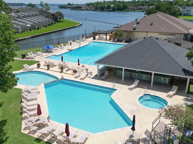 community pool featuring a community hot tub, a patio area, fence, and a water view