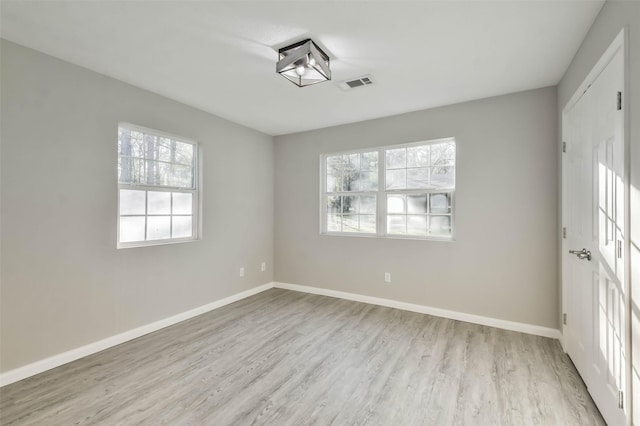 unfurnished room featuring visible vents, baseboards, and wood finished floors