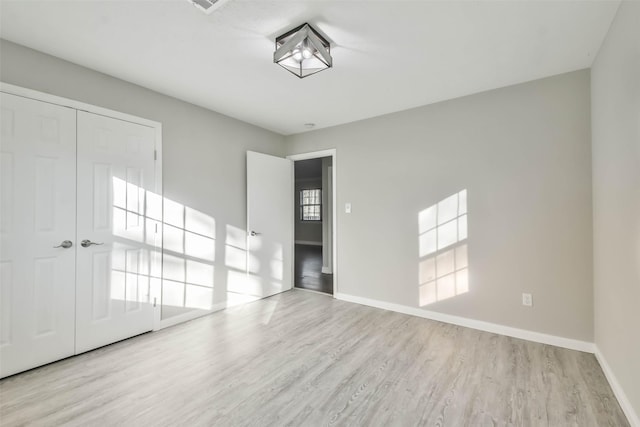 unfurnished bedroom with a closet, baseboards, and wood finished floors