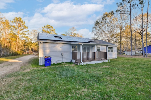 rear view of house with driveway, roof mounted solar panels, and a lawn