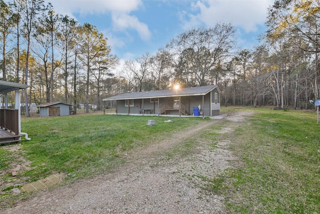 back of property featuring a storage shed, dirt driveway, a lawn, and an outdoor structure