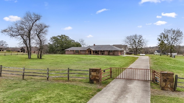 view of front facade featuring a front lawn, a rural view, fence, and a gate