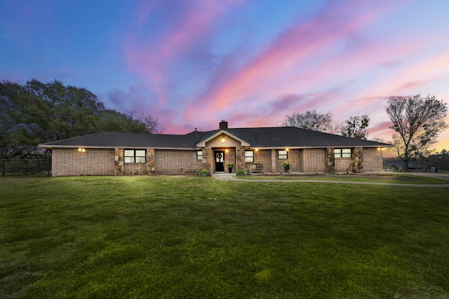 single story home featuring a chimney, a lawn, and brick siding