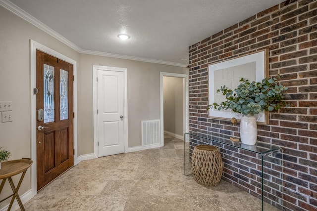 entrance foyer featuring a textured ceiling, brick wall, visible vents, baseboards, and crown molding