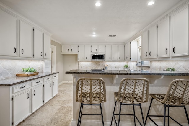 kitchen with white cabinetry, visible vents, and stainless steel microwave