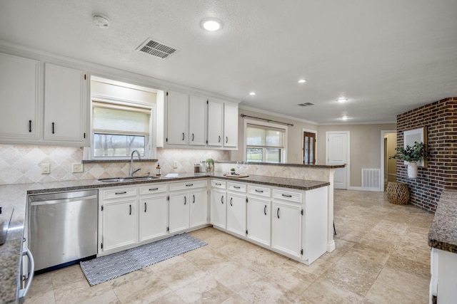 kitchen featuring visible vents, white cabinets, a sink, dishwasher, and a peninsula