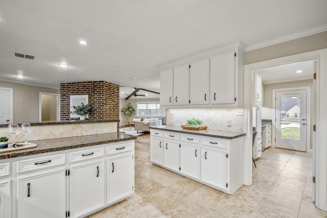 kitchen with crown molding, visible vents, backsplash, white cabinets, and dark stone counters