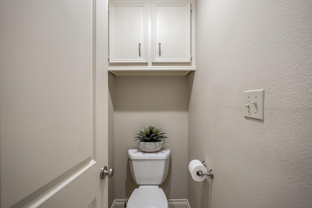 bathroom with a textured wall and toilet