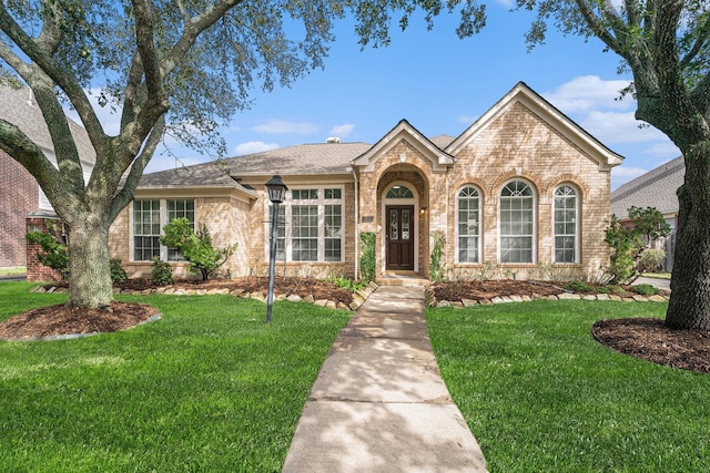 view of front facade with brick siding and a front yard