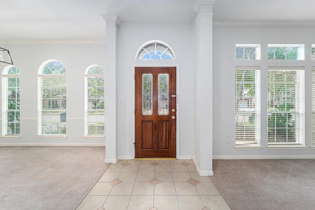 foyer with a wealth of natural light, light carpet, crown molding, and ornate columns