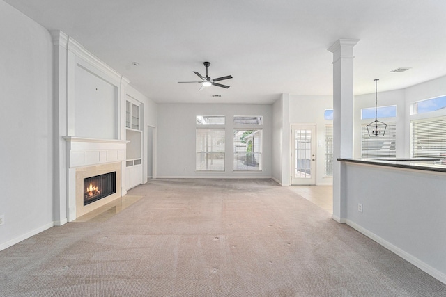 unfurnished living room featuring ceiling fan, a healthy amount of sunlight, a fireplace, and light colored carpet