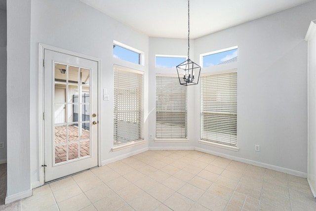 unfurnished dining area with an inviting chandelier, baseboards, and light tile patterned floors