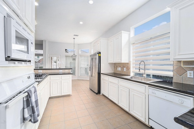 kitchen featuring dark countertops, stainless steel appliances, light tile patterned flooring, and a sink