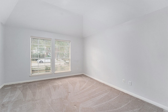 empty room with vaulted ceiling, carpet flooring, and baseboards