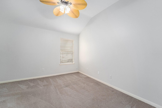 empty room featuring lofted ceiling, carpet floors, ceiling fan, and baseboards