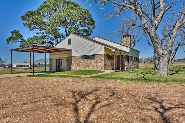 exterior space with brick siding, driveway, a chimney, and a lawn
