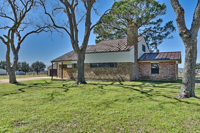 exterior space featuring brick siding, a front yard, a standing seam roof, metal roof, and a garage