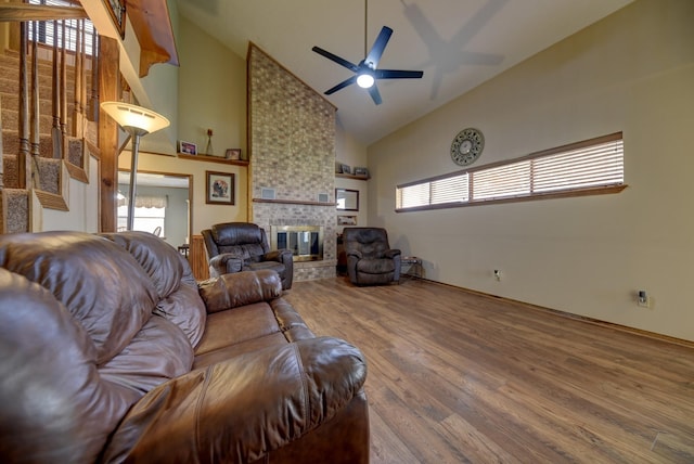 living room featuring ceiling fan, high vaulted ceiling, a fireplace, and wood finished floors