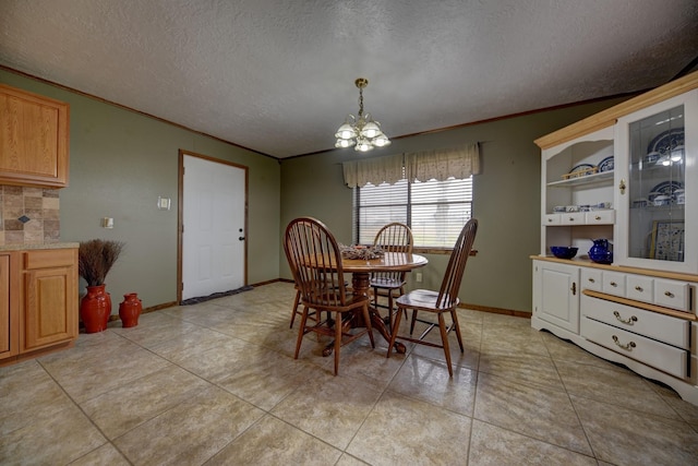 dining area with crown molding, a textured ceiling, light tile patterned flooring, and an inviting chandelier